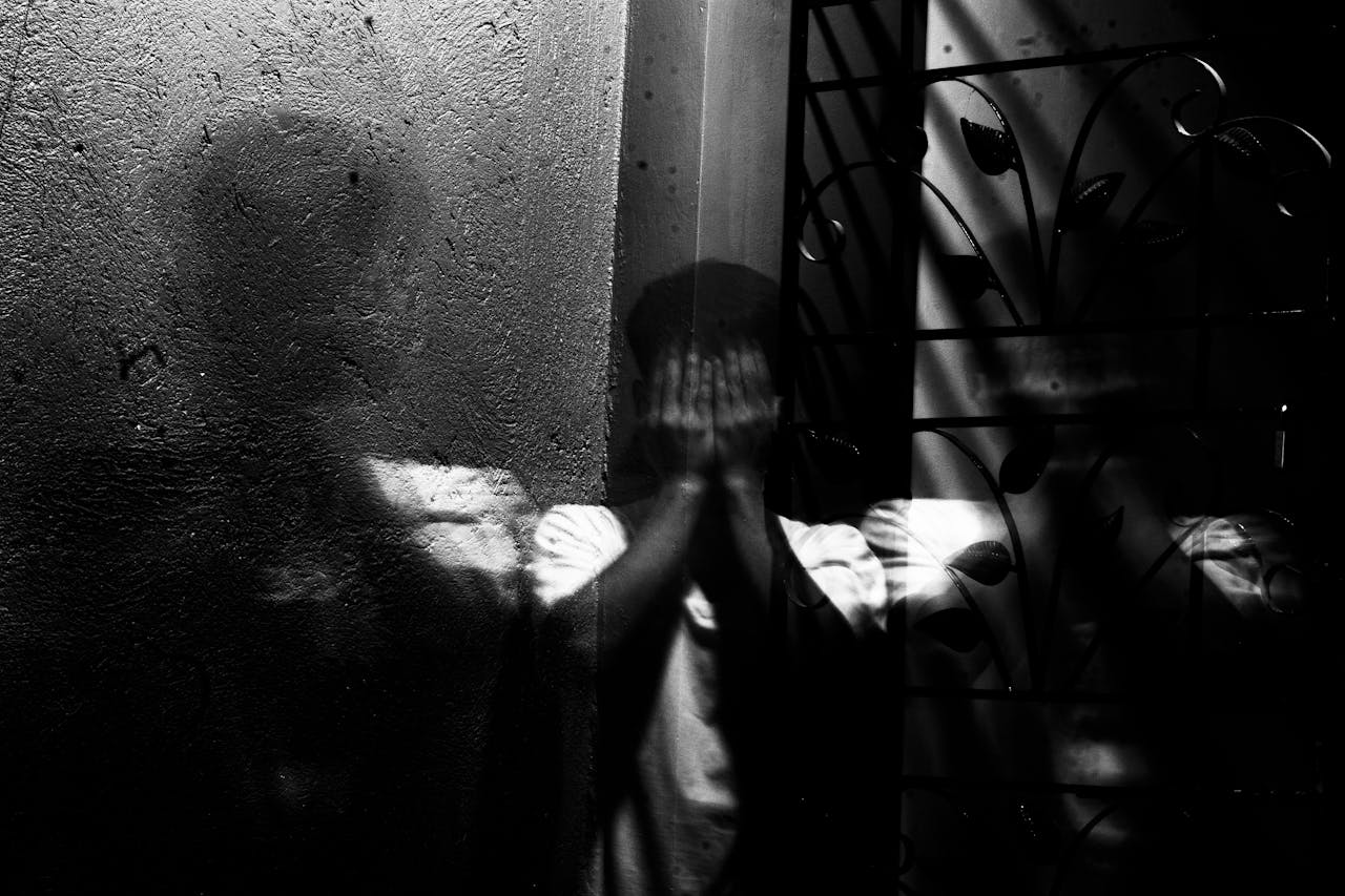 services-01 Grayscale image of a man covering his face, evoking themes of fear and introspection.